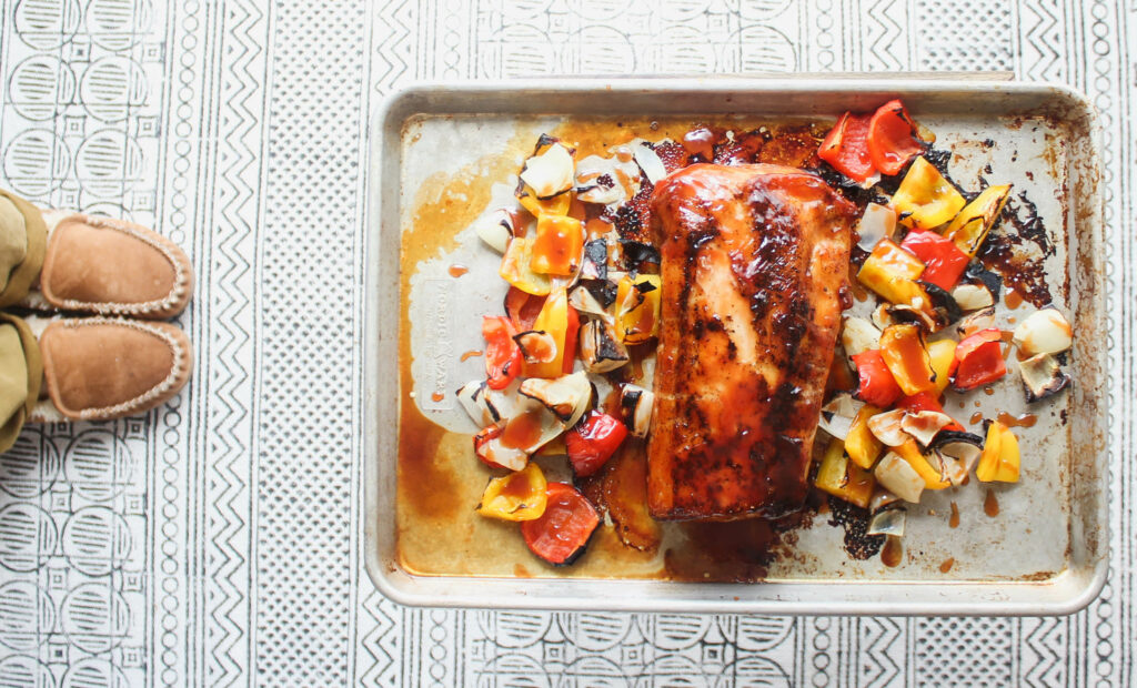 The finished sheet pan of Pork Loin Roast basted in sweet and sour sauce and roasted with peppers and onions.