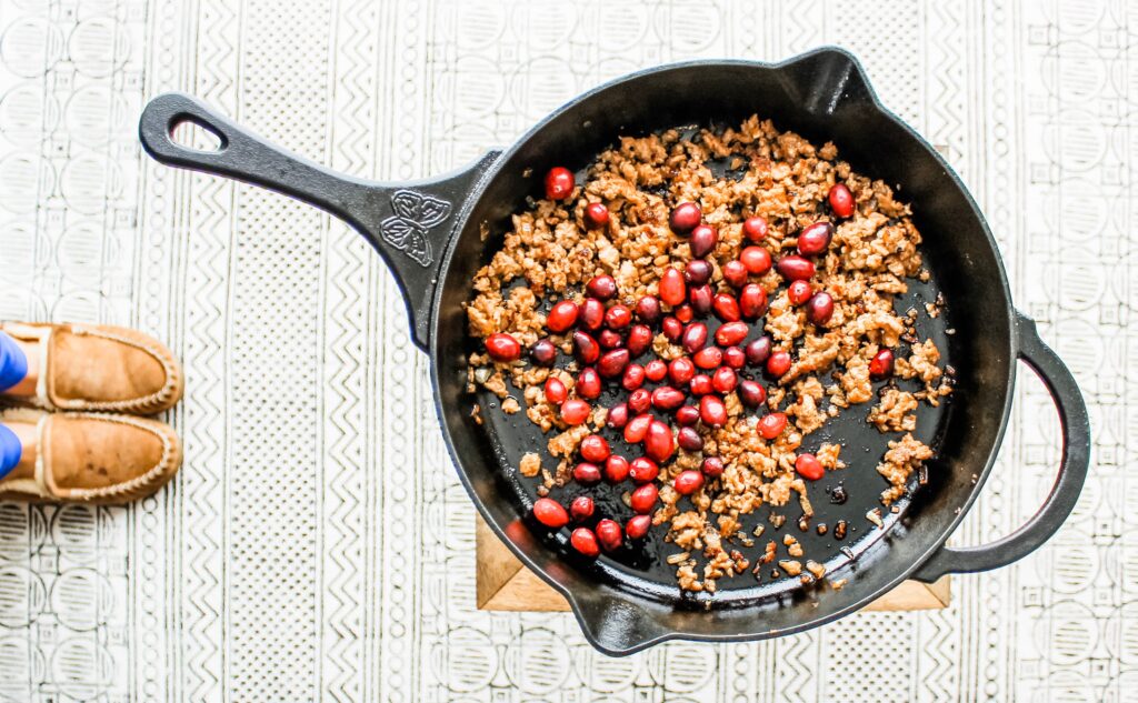 Cranberries and sweet Italian sausage cooking in a cast iron.