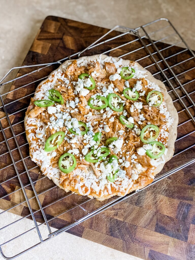 Easy buffalo chicken pizza on a baking rack before going into the oven. 