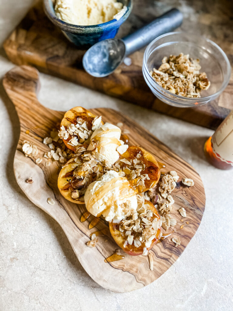 wood block of grilled peaches topped with ice cream, granola and hot honey drizzle. 
