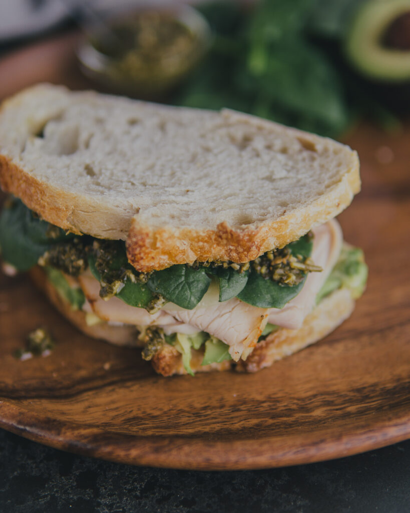 Pesto Avocado Turkey Sandwich on a wooden platter.