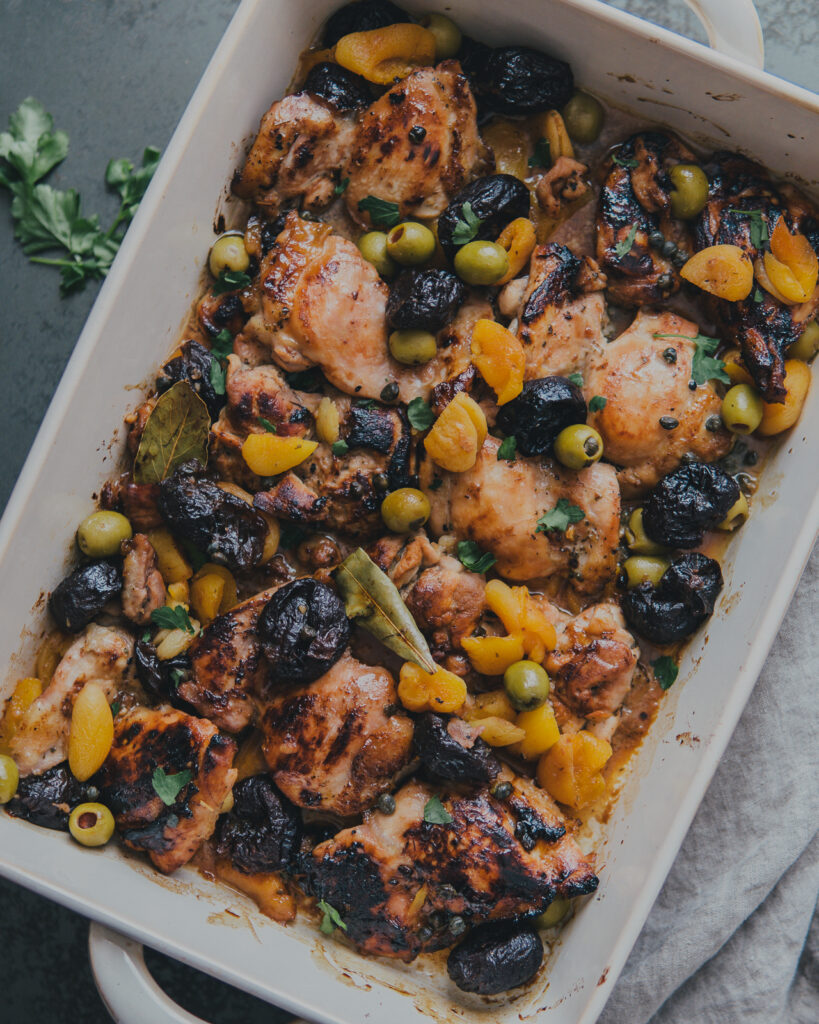 Finished Chicken Marbella with Apricots & Olives in a roasting pan.