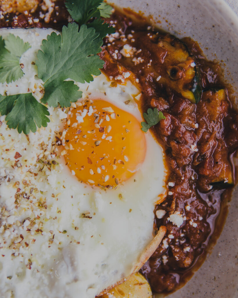 close up on bowl of Sunday Brunch Shakshuka with a fried egg on top. 