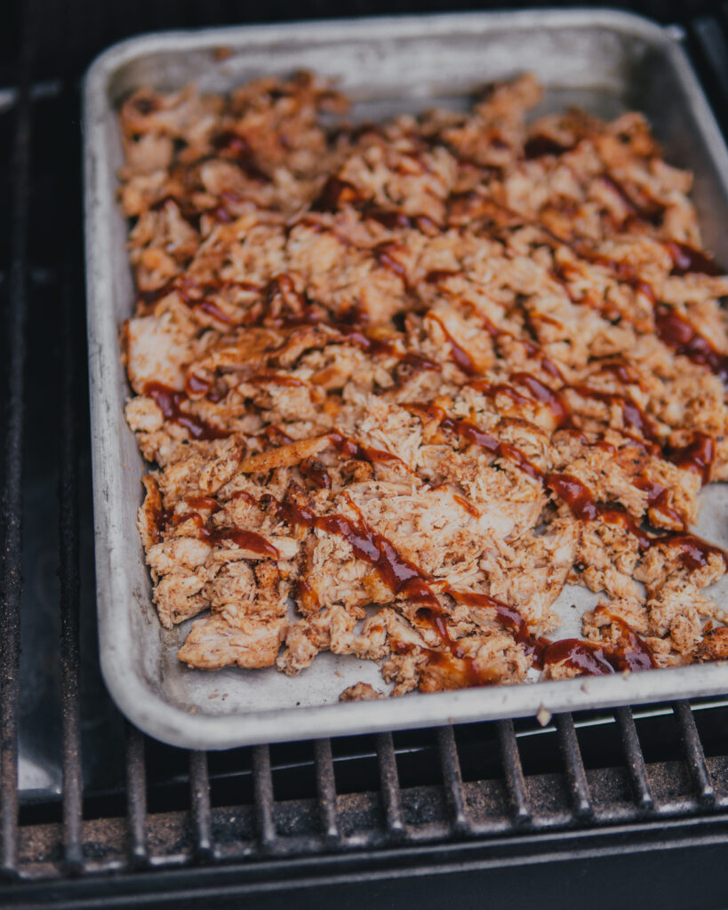 Sheet pan of shredded smoked chicken and bbq sauce.