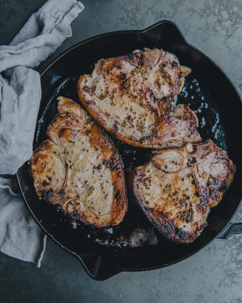 Bone-in pork chops cooked in a cast iron skillet
