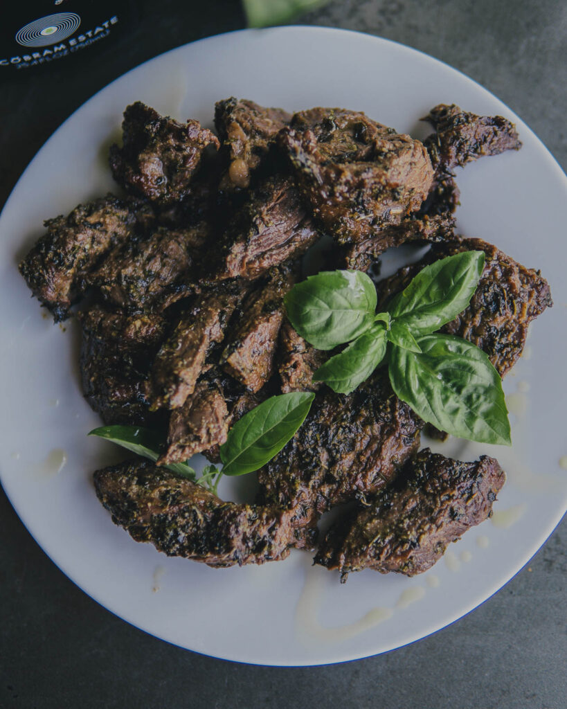 AirCrisp Steak Tips plated with fresh basil and a drizzle of olive oil. 