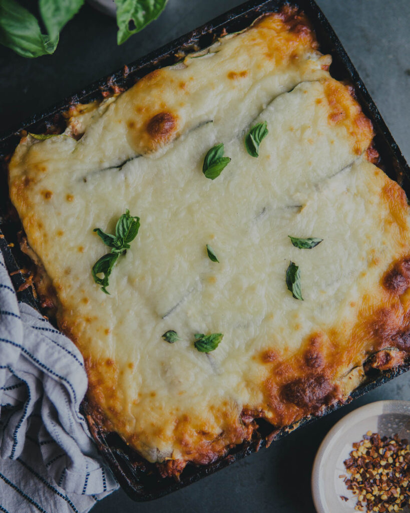 Cast iron zucchini lasagna with fresh basil on top
