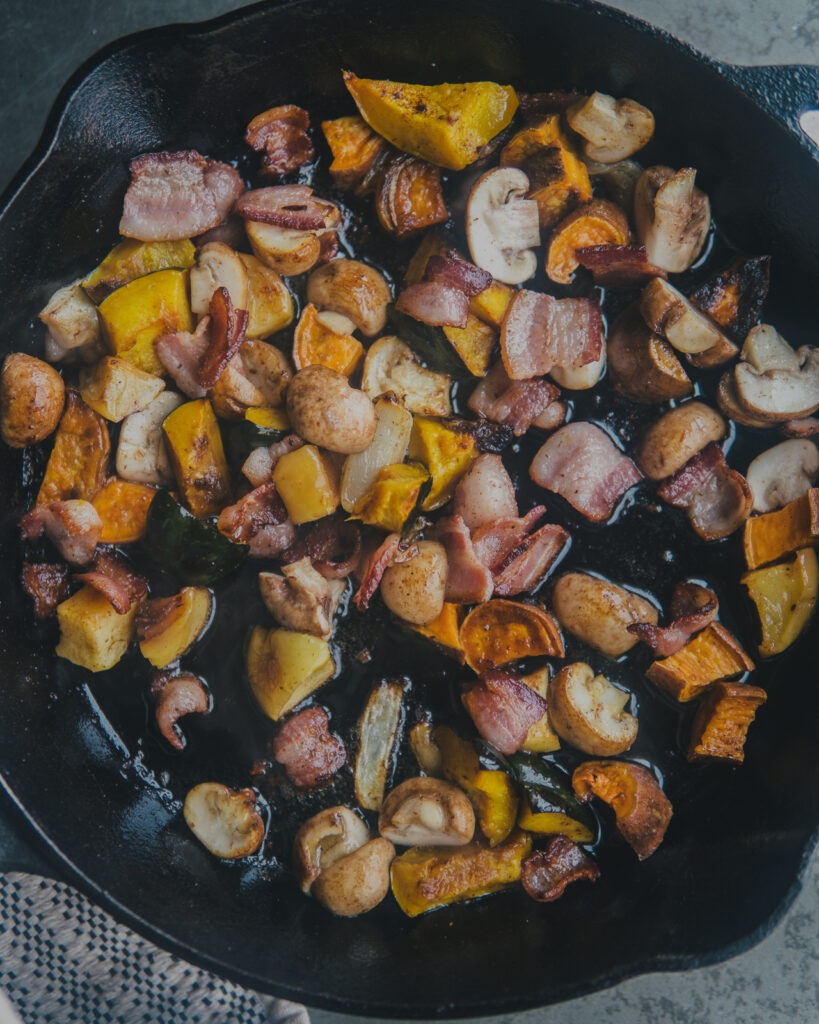 Bacon and veggies in a cast iron pan. 