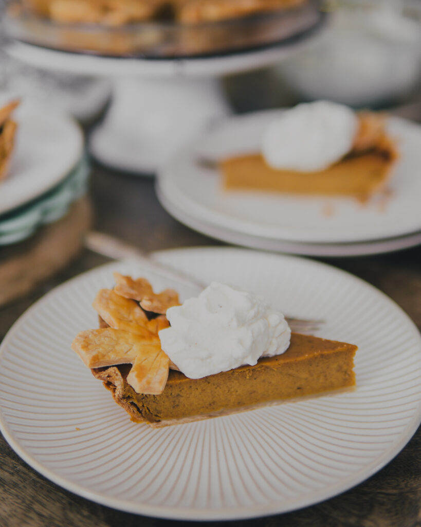 Slice of smoked pumpkin pie with eggnog whipped cream on a plate. 