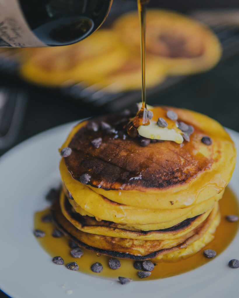 Pumpkin pancakes stacked drizzled with maple syrup. 